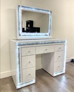 a white desk with a mirror and lights on the top, in front of a wall