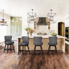 a large kitchen with wooden floors and white walls, along with an island in the center