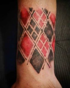 a tattoo on the wrist that looks like it has been painted with red and black squares