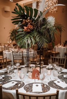 the table is set with white linens, silverware and greenery for an elegant centerpiece