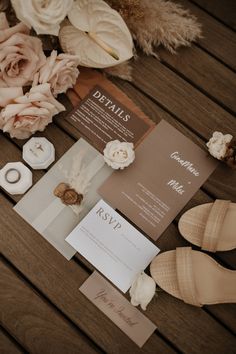 the wedding stationery is laid out on a wooden table with dried flowers and buttons