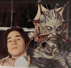 a young man standing next to a giant creature with horns on it's head