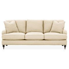 a cream colored couch with pillows on top of the armrests and back cushions