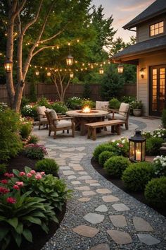 an outdoor dining area with lights strung over the table and chairs, surrounded by landscaping