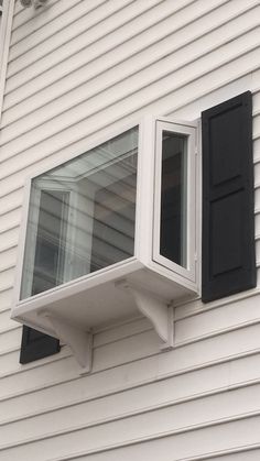 an air conditioner mounted to the side of a white house with black shutters