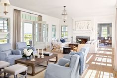 a living room filled with white furniture and lots of windows covered in curtains on either side of the couches