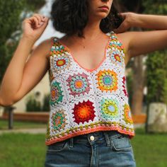 a woman wearing a crochet top in the grass with her hands on her hips