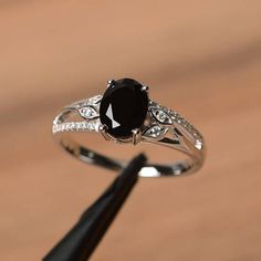 a black diamond ring sitting on top of a piece of wood next to a pen