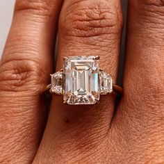 a woman's hand holding an emerald and diamond ring