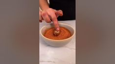 a person is dipping something into a bowl with some kind of sauce in it on the counter