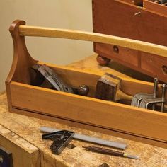 a wooden box filled with tools on top of a workbench and some drawers