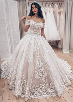 a woman standing in front of a mirror wearing a wedding dress with flowers on it