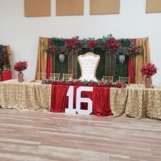 the table is decorated with red roses and gold chairs for an elegant wedding or special event