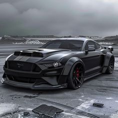 a black car parked on top of a snow covered parking lot next to a mountain