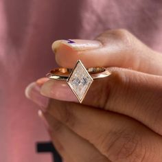 a close up of a person holding a ring with a diamond on the middle of it