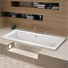 a large white bath tub sitting on top of a counter next to a shelf with towels