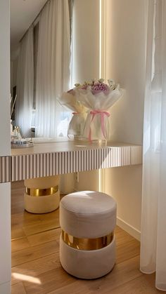 a white stool sitting next to a mirror on top of a wooden floor