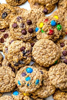 cookies with chocolate chips and m & m's are on a white plate, ready to be eaten