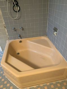 a bathtub sitting in the middle of a tiled floor next to a shower head