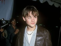 a young man wearing a leather jacket and blue shirt