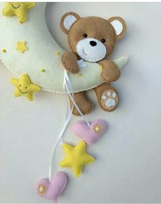 a teddy bear sitting on the moon with stars hanging from it's back end