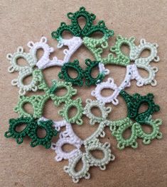 several crocheted green and white flowers on a brown surface