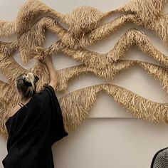 a woman in black shirt working on an art piece with long fringes and scissors