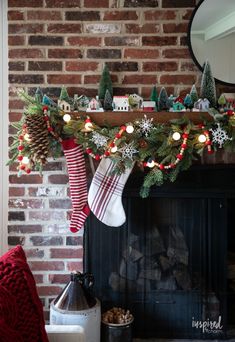 a mantel with stockings and christmas decorations on it, next to a fire place