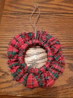 a red and green plaid wreath hanging on a wooden table