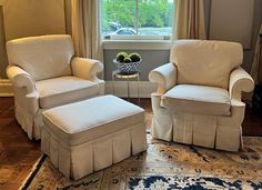 two chairs and a footstool in front of a window with a rug on the floor