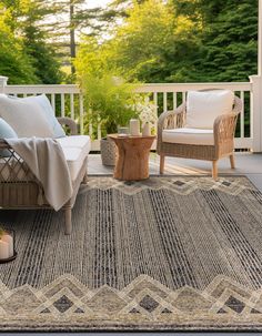 a porch with two chairs and a rug on the floor next to a couch, coffee table and potted plant