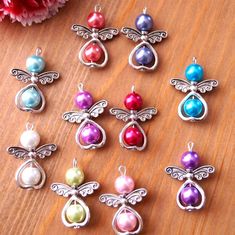 six charms with different colors and designs on top of a wooden table next to flowers