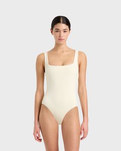 Margot one piece in Porcelain is a timeless classic swimsuit has an elegant square neckline front and back and invisible under-bust support. Self-lined in our ultra-soft Embodee™ fabric that has high shaping power, gently holding, shaping and enhancing the silhouette. To ensure the garment is opaque when wet, the front of the suit is a triple layer. A beautiful, classic one piece that will show off your summer tan and in a soft, matte fabric works perfectly as a body suit worn under skirts, shorts and pants. Luxury fabric sustainably made in Italy.Garment sustainably and ethically made in Australia. White Square Neck Swimwear For Beach, White Square Neck Swimwear For Swimming, Elegant Square Neck Stretch Swimwear, Modern Smoothing Swimwear For Summer, Modern Smoothing Swimwear, Elegant Square Neck Bodysuit, Square Neck Swimwear With Lined Body, Elegant Swimwear With Seamless Construction, Elegant Second-skin Swimwear With Moderate Back Coverage