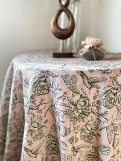 a table topped with a vase filled with flowers next to a wooden sculpture on top of it