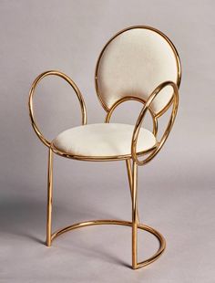 a gold chair with white upholstered fabric on the seat and back, in front of a gray background