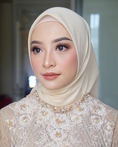 a woman wearing a white hijab with pearls on her neck and headband