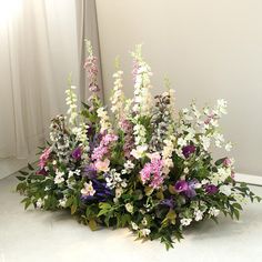 a basket filled with lots of flowers on top of a white floor next to a window