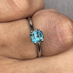 a woman's hand wearing a ring with an aqua blue topazte