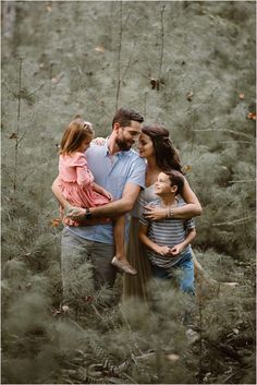 a man and two girls hugging each other while standing in the middle of tall grass