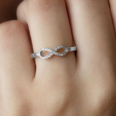 a woman's hand with a white gold ring on it that has an infinite knot in the middle