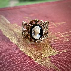 Victorian style antiqued brass filigree ring which is fully adjustable.At its center is a 10x8mm black and white womans profile cameo.   Other cameo color options are available as well.Also available in antiqued silver. Womans Profile, Gold Marquise Ring, Silver Celtic Rings, Opal Solitaire Ring, Turquoise Statement Ring, White Lady, Purple Lady, Turquoise Gold Ring, White Opal Ring