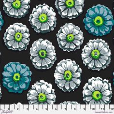 a black and white flower with green centers on it's center is shown in front of a ruler