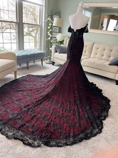 a black and red dress on display in front of a white couch with a large window behind it