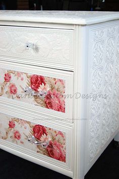 a white dresser with pink flowers painted on it