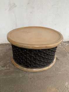 a round wooden table sitting on top of a cement floor