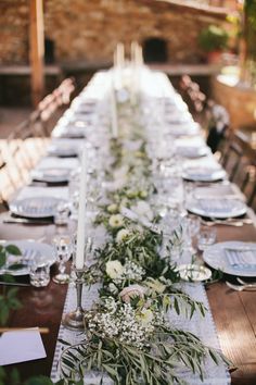 the long table is set with white flowers and greenery