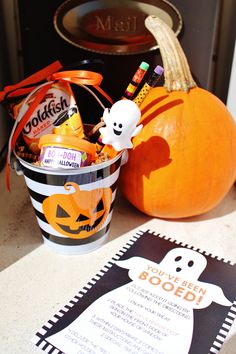 a bucket filled with candy next to a pumpkin