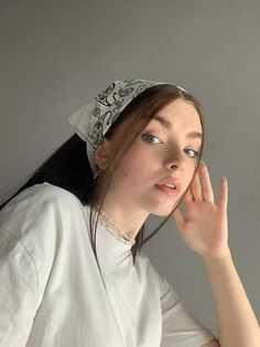 a woman with a bandana on her head is posing for the camera and holding her hand up to her face