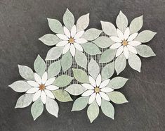 some white flowers are sitting on a black table top with green leaves and mesh in the middle