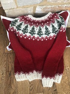 a red and white sweater sitting on top of a wooden floor